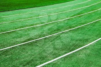 Running track background with bright green artificial turf and lines