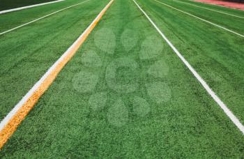 Empty running track perspective with artificial turf field and lines