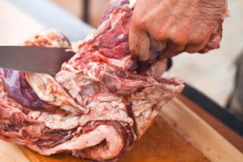 Raw lamb cutting, cook hand with knife, close-up photo, selective focus