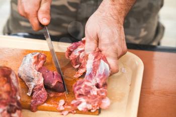 Raw lamb meat cutting, cook hands with knife, close-up photo, selective focus