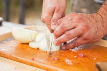 White onion slicing. Cook hands with knife, close-up photo, selective focus