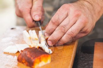 Smoked lard slicing on wooden board. Cook hands with knife, close-up photo, selective focus