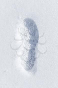 Foot imprint in fresh white snow, close-up top view