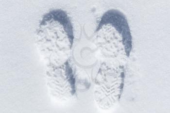 Feet imprint in white snow, close-up top view