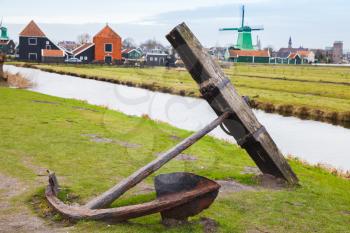 Old rusted anchor on coast of Zaan river. Zaanse Schans historic town, popular tourist attraction of Netherlands