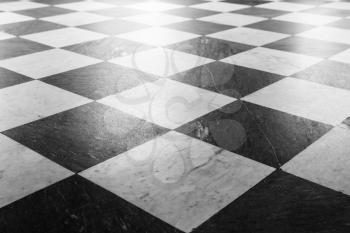 Shiny stone floor tiling with classical black and white checkered pattern