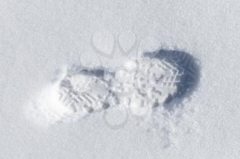 Foot imprint in white snow, close-up top view