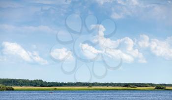 Rural Russian landscape with Volkhov River coast under blue cloudy sky in summer day. Novgorod Oblast, Russia