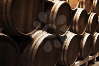 Wine production. Round wooden barrels in dark winery, close up photo with selective focus