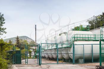 White steel tanks behind green fence, modern wine factory equipment