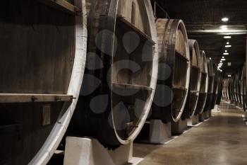 Large vintage wooden barrels in winery basement, close up photo with selective focus