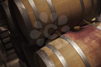 Wooden barrels with red wine in dark winery, close up photo with selective focus