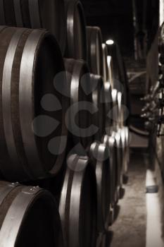 Wooden barrels in dark winery, close up vertical photo with selective focus