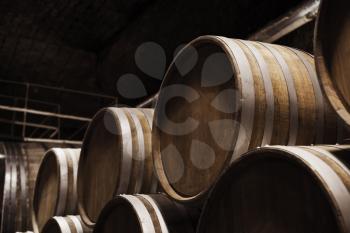 Round wooden barrels in dark winery, close up photo with selective focus