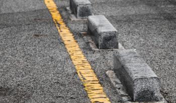 Concrete road side border blocks and yellow dividing line. Close-up photo with selective focus