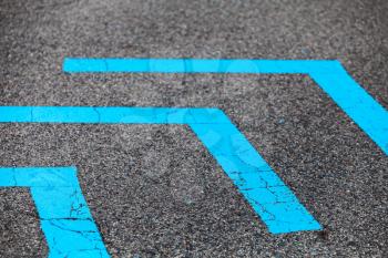 Corners of blue lines over dark asphalt, close-up photo with selective focus