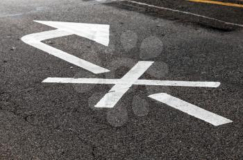 Right turn is prohibited. Crossed white arrow, road marking over black highway asphalt. Close-up photo with selective focus