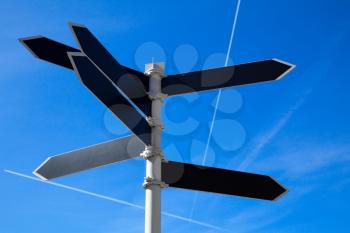 Empty guidepost with arrow shaped labels over blue sky background