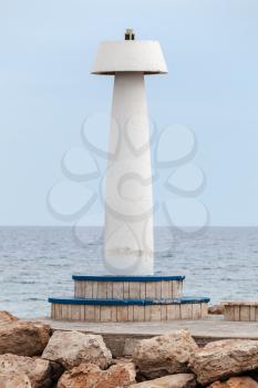 White lighthouse tower standing on a breakwater at the entrance to Ayia Napa port, Cyprus, Mediterranean Sea