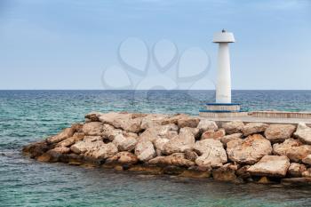White lighthouse tower standing on breakwater at the entrance to Ayia Napa port. Cyprus, Mediterranean Sea