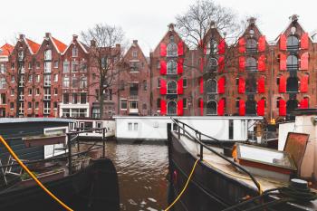 Traditional living houses made of red bricks stand along canal in Amsterdam, Netherlands