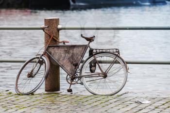 Old rusted bicycle is on the embankment in Bergen harbor, Norway