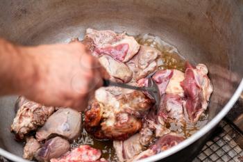 Mixing lamb pieces in a cauldron. Preparing of Chorba soup on open fire, traditional meal for many national cuisines in Europe, Africa and Asia 