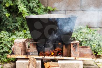 Cauldron boiling on bonfire. Preparing of Chorba soup, traditional meal for many national cuisines in Europe, Africa and Asia 