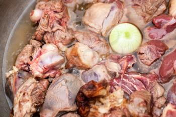 Lamb pieces with whole onion stew in a cauldron. Preparing of Chorba soup on open fire, traditional meal for many national cuisines in Europe, Africa and Asia 