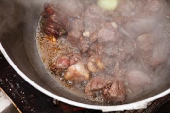 Lamb with onion boiling in a cauldron on bonfire. Preparing of Chorba soup, traditional meal for many national cuisines in Europe, North Africa and Asia 