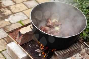 Lamb with onion boiling in a cauldron on bonfire. Preparing of Chorba soup, traditional meal for many national cuisines in Europe, Africa and Asia 