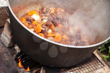 Lamb with carrot and onion stew in a cauldron. Preparing of Chorba soup on open fire, traditional meal for many national cuisines in Europe, Africa and Asia 