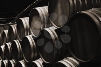 Wooden barrels in dark wine factory hall, close up photo monochrome with selective focus