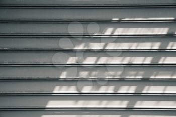 Gray metal roller shutter door with shadows pattern. Background photo texture, front view