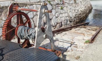 Old rusted winch for lowering and raising boats to water in the port