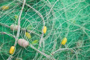 Drying green nylon fishing net with yellow floats. Background photo