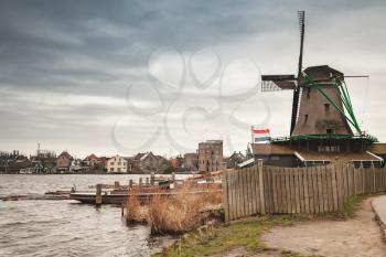 Windmill on river coast, Zaanse Schans town, popular tourist attractions of the Netherlands. Suburb of Amsterdam