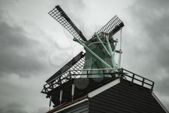 Windmill under dramatic cloudy sky. Zaanse Schans town, popular tourist attractions of the Netherlands. Suburb of Amsterdam