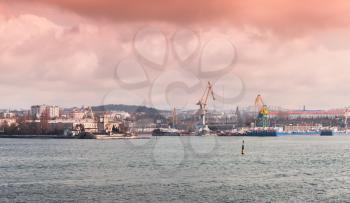 Sevastopol Bay, coastal cityscape with port cranes under colorful cloudy sky
