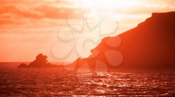 Portugal. Porto Santo island. Landscape with coastal rocks in red evening sunlight. Red tonal filter effect