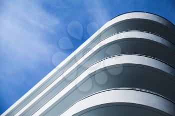 Abstract modern architecture, round white concrete facade under blue cloudy sky