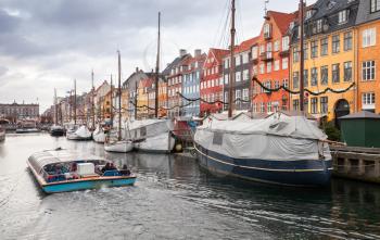 Tourist boat goes on Nyhavn or New Harbour, it is a 17th-century waterfront, canal and popular touristic district in central Copenhagen, Denmark