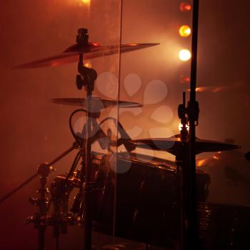 Live rock music photo background, rock drum set  with cymbals in smoke and red lights. Close-up photo, soft selective focus