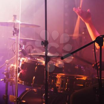 Drummer hand with drumsticks near rock drum set. Warm toned closeup photo, soft selective focus
