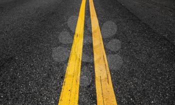 Yellow double dividing lines perspective view, highway road marking on dark asphalt