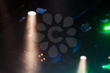 Scenic spot lights beams in smoke over dark background, modern stage illumination equipment