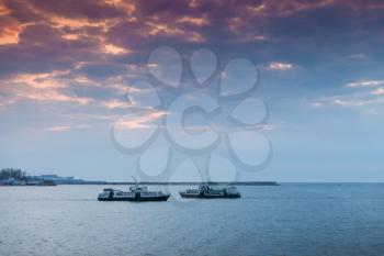 Two small passenger ships go under colorful evening sky. Landscape of Sevastopol Bay in sunset