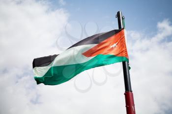 National flag of Jordan waving on wind over cloudy sky