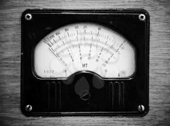 Close-up monochrome photo of vintage electric voltmeter in wooden panel