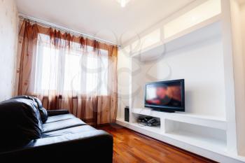 Empty living room interior with black leather sofa and tv in white installation